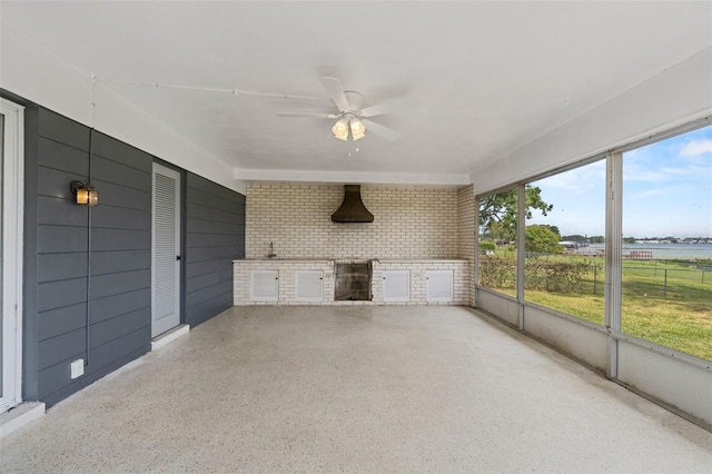 unfurnished sunroom featuring exterior kitchen and a ceiling fan