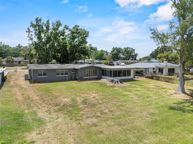 rear view of house featuring a yard, a sunroom, and fence