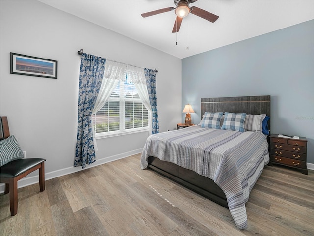 bedroom with a ceiling fan, wood finished floors, and baseboards