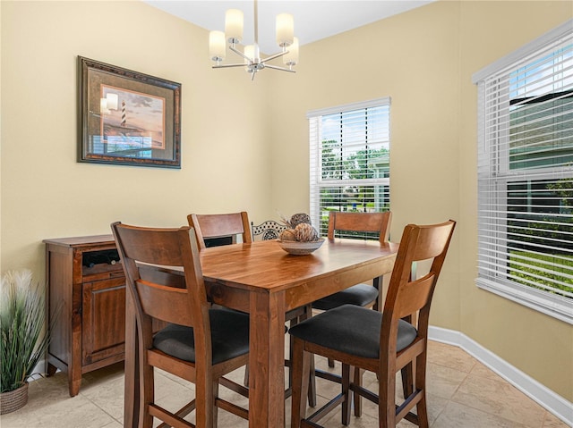dining space with baseboards, a notable chandelier, and light tile patterned flooring