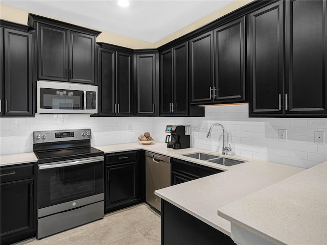 kitchen with backsplash, stainless steel appliances, dark cabinetry, and a sink