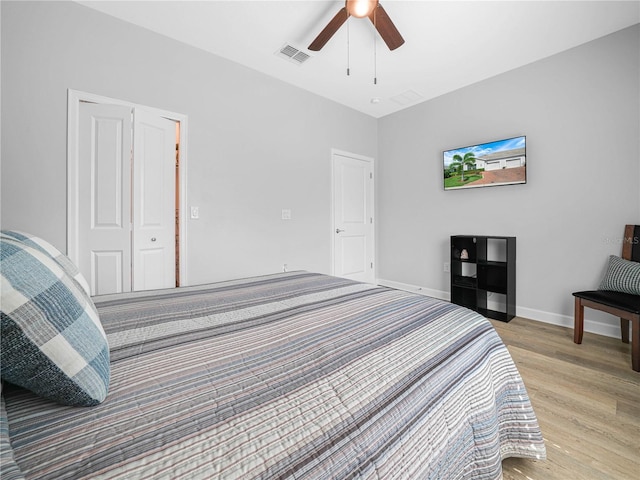 bedroom featuring baseboards, a ceiling fan, visible vents, and light wood-style floors