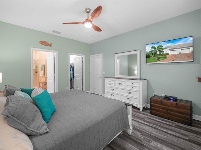 bedroom featuring connected bathroom, a ceiling fan, visible vents, dark wood-style flooring, and a spacious closet