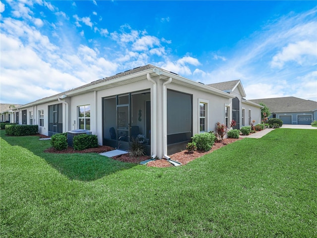 rear view of property featuring a yard, stucco siding, and a sunroom
