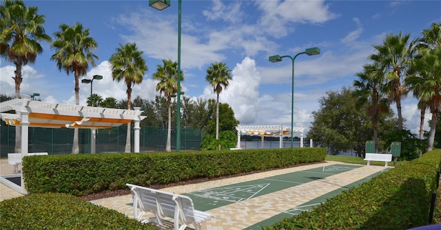 view of home's community featuring a pergola, fence, and shuffleboard