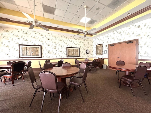carpeted dining room with a tray ceiling, wainscoting, a ceiling fan, and wallpapered walls