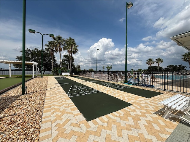 view of community with fence and shuffleboard