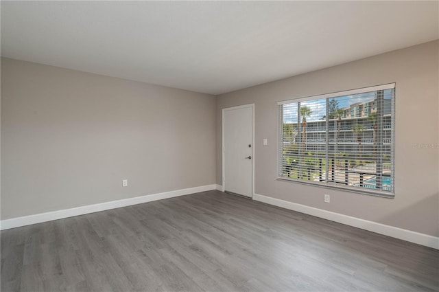 empty room with baseboards and dark wood-style floors