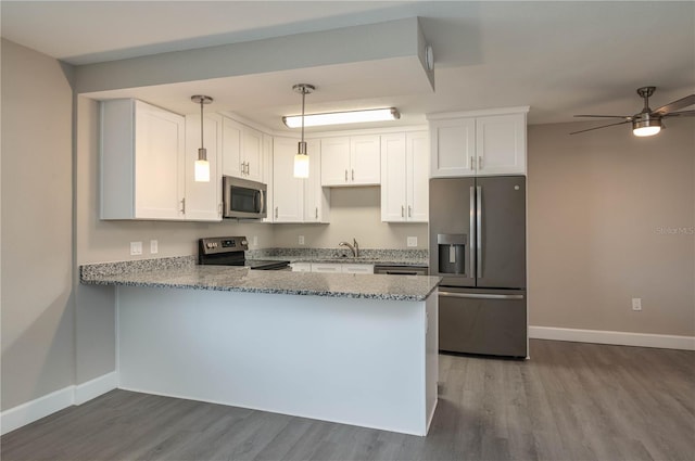 kitchen with a peninsula, stainless steel appliances, baseboards, and dark wood-type flooring