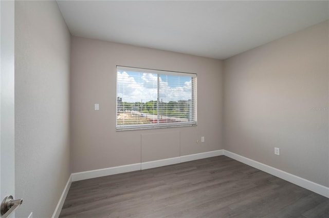 spare room featuring wood finished floors and baseboards
