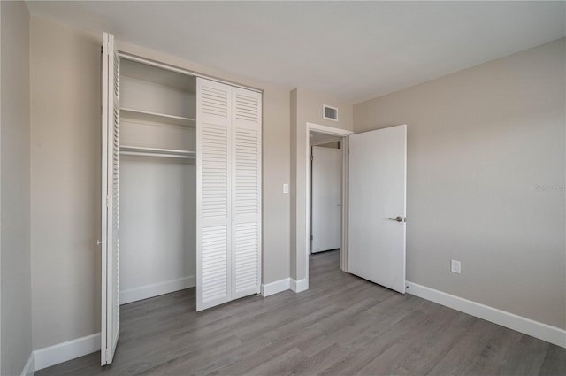 unfurnished bedroom featuring baseboards, visible vents, and wood finished floors