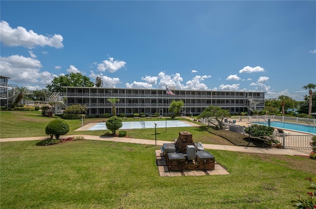 view of property's community featuring a lawn, fence, shuffleboard, and a swimming pool