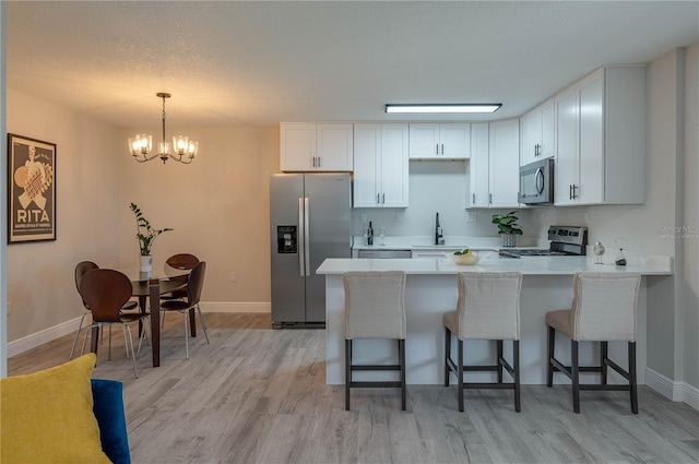 1700 6th St NW Unit C26, Winter Haven, FL 33881 - kitchen with appliances with stainless steel finishes, a peninsula, a chandelier, and baseboards