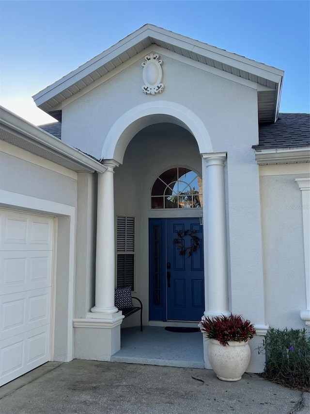 135 Minniehaha Cir, Haines City, FL 33844 - entrance to property with stucco siding, a garage, and a shingled roof