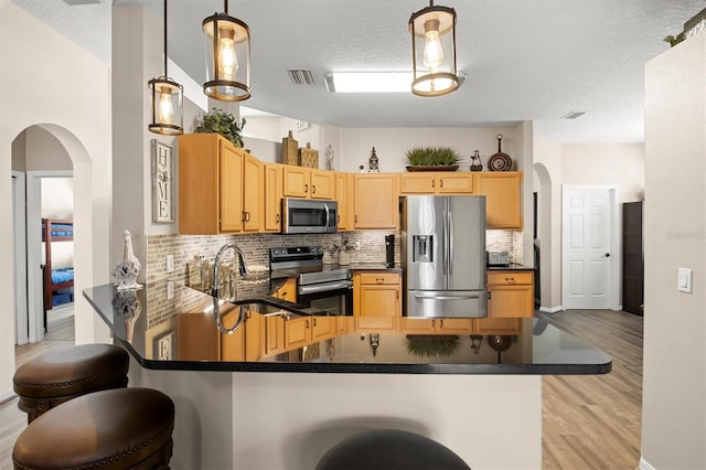 135 Minniehaha Cir, Haines City, FL 33844 - kitchen featuring stainless steel appliances, dark countertops, a peninsula, a sink, and arched walkways