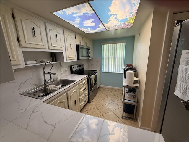 333 Lake Howard Dr NW Unit 103C, Winter Haven, FL 33880 - kitchen featuring appliances with stainless steel finishes, a sink, decorative backsplash, light tile patterned floors, and white cabinetry