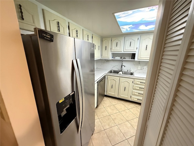 333 Lake Howard Dr NW Unit 103C, Winter Haven, FL 33880 - kitchen with a sink, stainless steel appliances, light tile patterned floors, light countertops, and a skylight