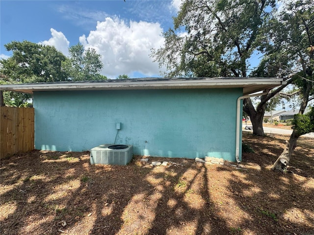 view of home's exterior featuring central AC, fence, and stucco siding