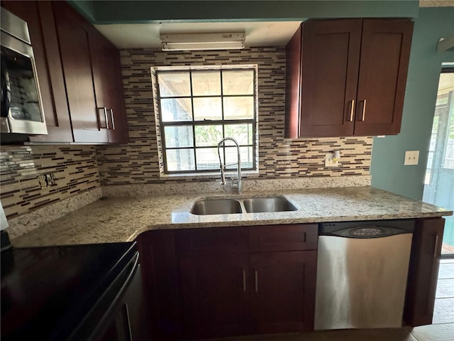 kitchen with appliances with stainless steel finishes, a sink, backsplash, and light stone countertops