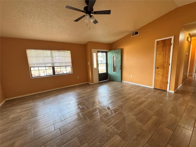 empty room with vaulted ceiling, a ceiling fan, wood tiled floors, a textured ceiling, and baseboards