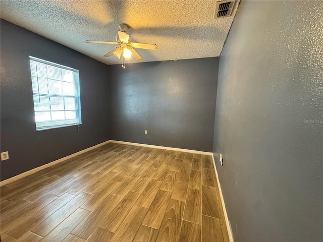 empty room with wood finished floors, ceiling fan, baseboards, and a textured ceiling