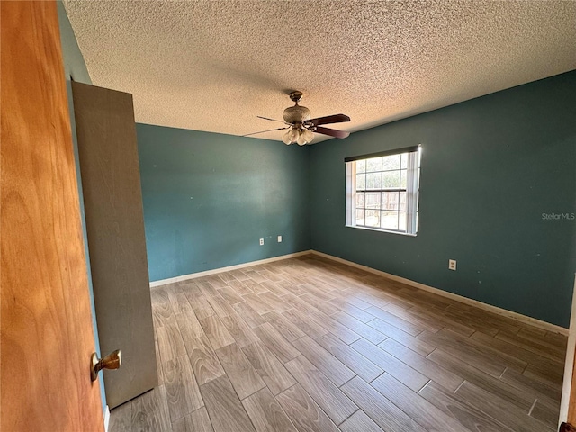 empty room featuring wood finished floors, a ceiling fan, a textured ceiling, and baseboards
