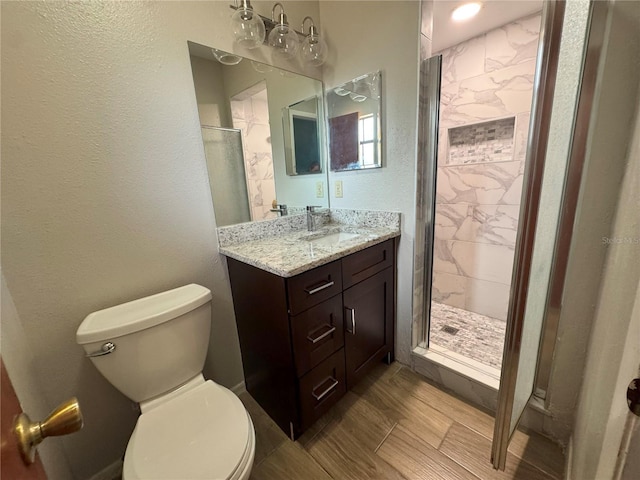 full bathroom featuring a shower stall, toilet, a textured wall, and vanity