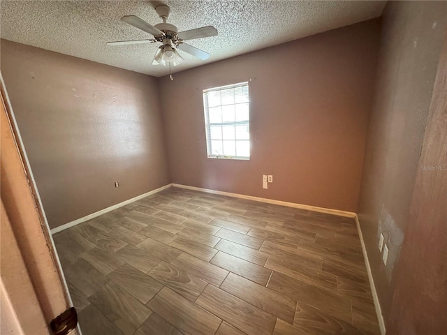 spare room featuring a ceiling fan, a textured ceiling, wood finish floors, and baseboards