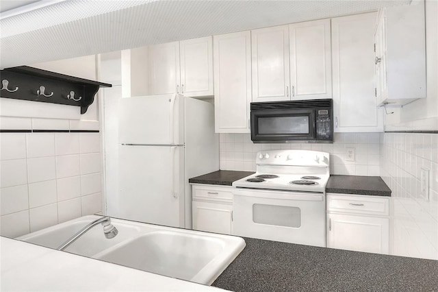 kitchen with white appliances, white cabinets, a sink, and dark countertops