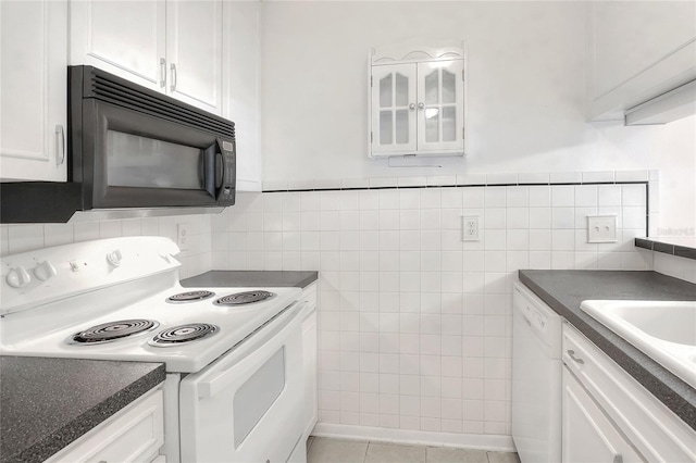 kitchen featuring white appliances, tile walls, white cabinetry, dark countertops, and glass insert cabinets