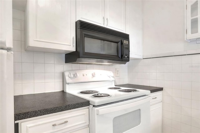 kitchen featuring white range with electric cooktop, black microwave, dark countertops, white cabinets, and decorative backsplash