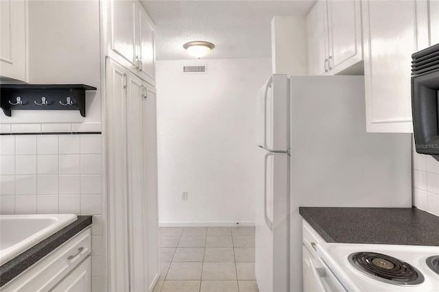 kitchen with white cabinets, white electric range oven, light tile patterned flooring, dark countertops, and a textured ceiling