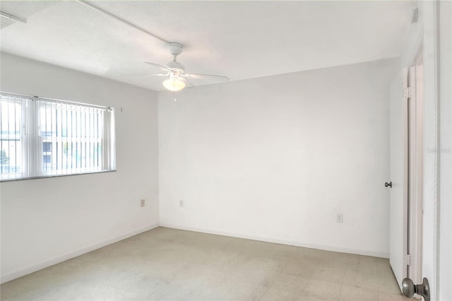 spare room with a ceiling fan and baseboards