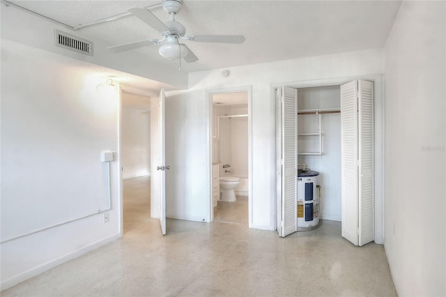 unfurnished bedroom with electric water heater, baseboards, concrete flooring, and connected bathroom