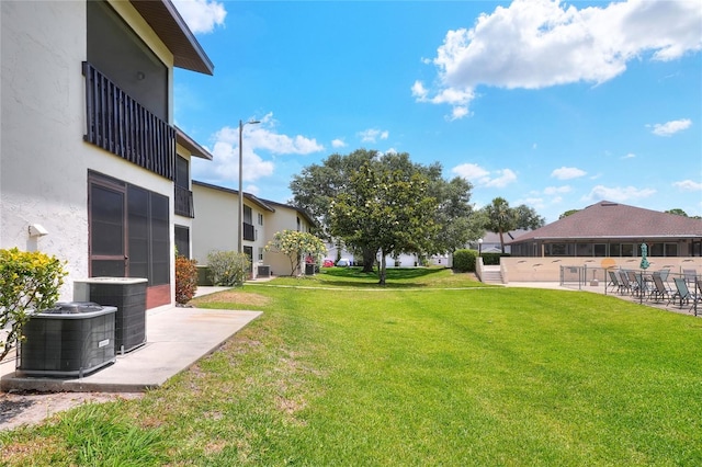 view of green lawn featuring central air condition unit, a patio area, and a residential view