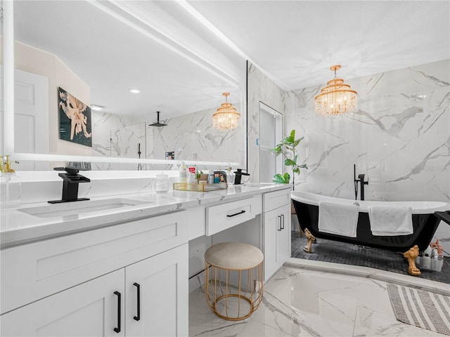 bathroom featuring stone wall, a chandelier, marble tiled floors, double vanity, and a freestanding bath