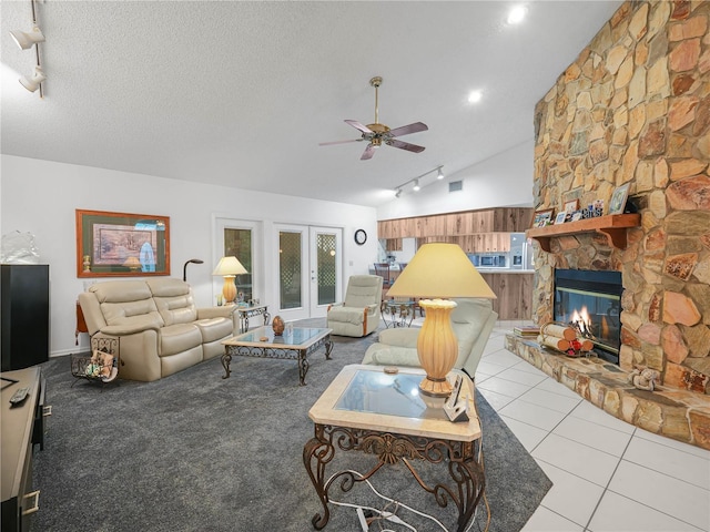 409 N 6th St, Lake Hamilton, FL 33851 - tiled living room with rail lighting, ceiling fan, vaulted ceiling, a fireplace, and a textured ceiling