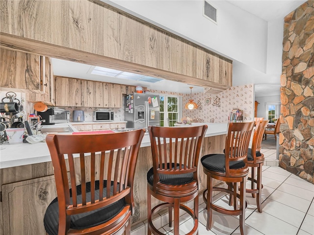 409 N 6th St, Lake Hamilton, FL 33851 - kitchen with white microwave, stainless steel refrigerator with ice dispenser, light countertops, a breakfast bar area, and light tile patterned flooring