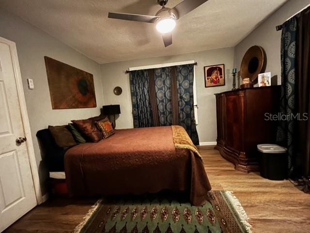 bedroom featuring wood finished floors, baseboards, and a ceiling fan