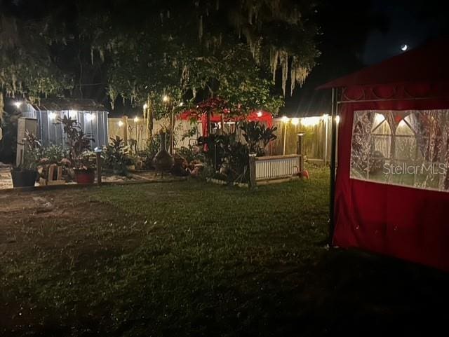 yard at night with a storage unit, an outbuilding, and a lawn