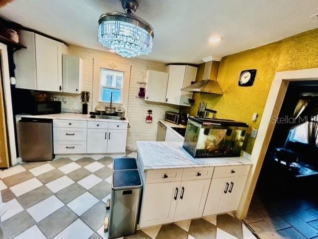 kitchen with wall chimney range hood, a sink, dishwasher, and white cabinetry