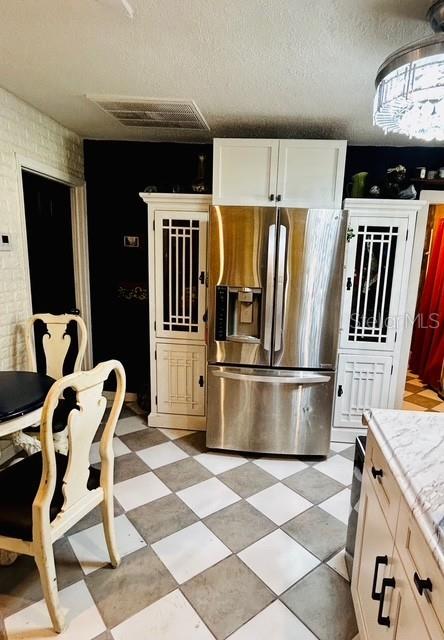 kitchen with stainless steel fridge with ice dispenser, light countertops, and a textured ceiling