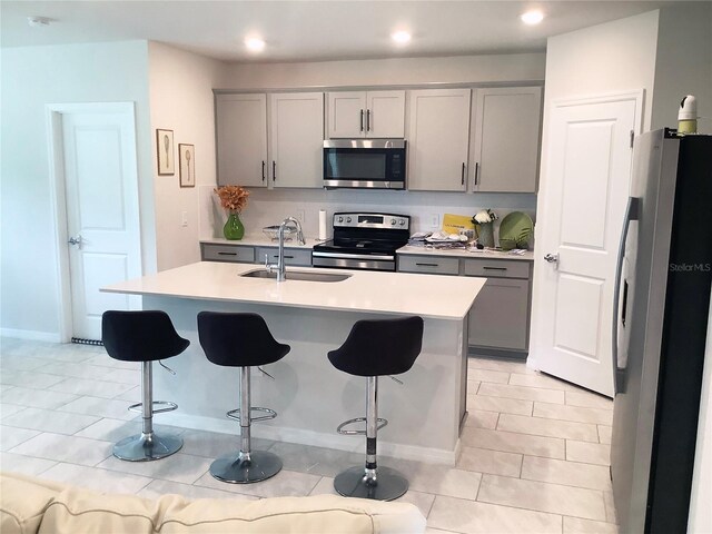 1050 Michelangelo Ln, Winter Haven, FL 33884 - kitchen with appliances with stainless steel finishes, gray cabinetry, a sink, a breakfast bar, and recessed lighting