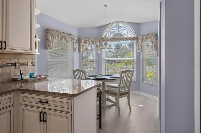 4005 Carter Creek Dr, Avon Park, FL 33825 - kitchen featuring decorative backsplash, a peninsula, light stone counters, baseboards, and cream cabinetry
