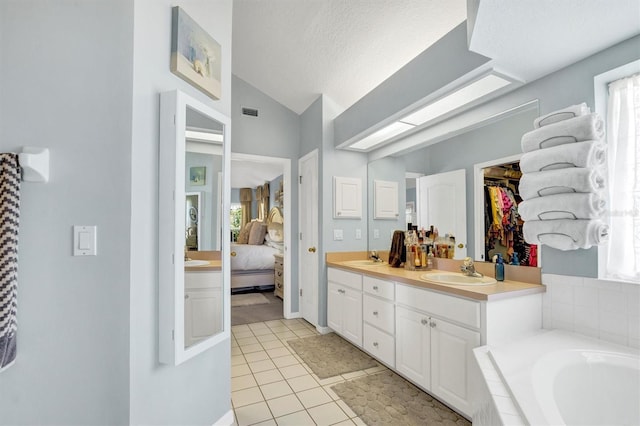 109 Lake Mariam Way, Winter Haven, FL 33884 - ensuite bathroom featuring lofted ceiling, double vanity, tile patterned floors, a textured ceiling, and tiled tub