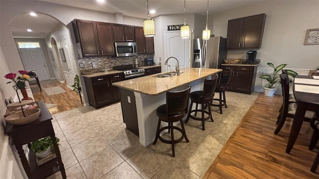 3828 Eloise Estates Ct, Winter Haven, FL 33881 - kitchen featuring stainless steel appliances, a sink, arched walkways, a kitchen breakfast bar, and dark brown cabinetry
