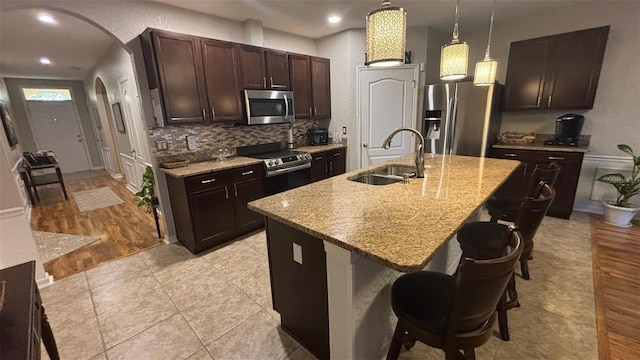 3828 Eloise Estates Ct, Winter Haven, FL 33881 - kitchen featuring a sink, stainless steel appliances, arched walkways, dark brown cabinetry, and a kitchen breakfast bar