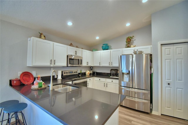879 Orleans Dr, Eagle Lake, FL 33839 - kitchen featuring appliances with stainless steel finishes, a peninsula, a sink, white cabinetry, and dark countertops