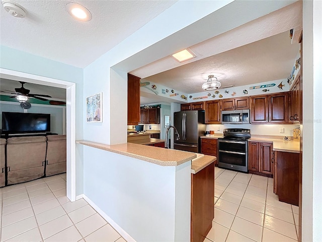 255 Lake Link Rd, Winter Haven, FL 33884 - kitchen with stainless steel appliances, light tile patterned floors, a textured ceiling, light countertops, and a peninsula