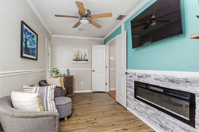 418 N Rd, Lakeland, FL 33809 - living area featuring a stone fireplace, a ceiling fan, wood finished floors, ornamental molding, and a wainscoted wall